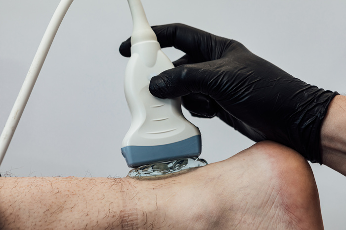 podiatrist doing a diagnostic ultrasound scan of the achilles tendon of a patient foot